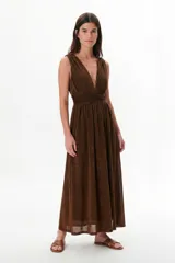 Vestido largo negro con brillo sutil, escote profundo en V y cintura marcada con frunces. Diseño sin mangas y falda amplia.