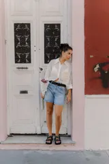 Cinturón de cuero negro con hebilla metálica circular plateada y diseño minimalista.