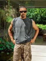 Musculosa sin mangas color gris oscuro con efecto lavado y bordes deshilachados. Presenta un estampado en relieve en el frente con texto en mayúsculas.