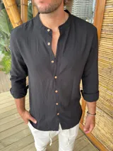 Camisa de cuello mao en color negro, confeccionada en tela liviana, con mangas largas y botones frontales en tono madera.