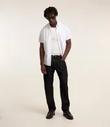 Camisa blanca con rayas celestes, de corte clásico, manga corta y cuello solapa. Confeccionada en fibra de bambú y poliéster.