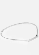 Cinto plateado de metal elastizado con placa rectangular en el frente.