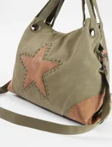 Bolso tipo shopper de gran capacidad confeccionado en lona color verde oliva, con detalles en cuero sintético color suela. Presenta una estrella central aplicada con tachas metálicas, doble asa de hombro y correa regulable extraíble.