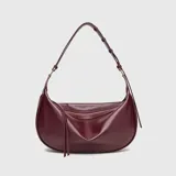 Cartera de ecocuero color bordó, de diseño curvo tipo hobo, con cierre superior deslizante y correa ajustable para el hombro.