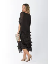 Vestido midi de seda italiana color negro, diseño dos en uno con capa superior de calce amplio, falda con volados y forro interior de algodón elastizado.