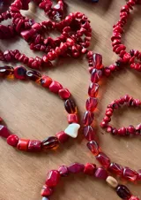 Collar de piedras naturales en tonos rojos, confeccionado con cuentas irregulares de coral y detalles en nácar blanco.