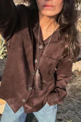 Sobrecamisa de tejido efecto ante en color marrón, con cuello solapa, manga larga con puños y cierre frontal de botones. Presenta un bolsillo de plastrón en el pecho.