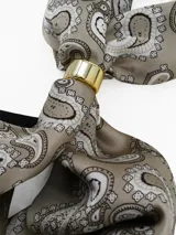 Pañuelo de seda con estampado geométrico en blanco, negro y gris, que incluye un anillo metálico dorado para sujetarlo.