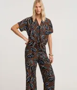 Pantalón tipo pantacourt de calce holgado y tiro alto, confeccionado en tejido de viscosa con estampa de follaje en tonos negro, blanco y azul sobre fondo marrón. Posee cintura elástica.