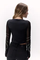 Remera negra de mangas largas transparentes, con apliques de brillos formando ondulaciones.