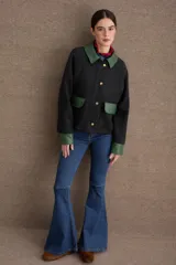 Campera corta en tono beige con cuello, puños, solapas de bolsillos frontales y detalles en cuero sintético marrón. Cuenta con cierre frontal de botones dorados y bolsillos aplicados.