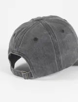 Gorra de béisbol color rojo oscuro o rosado viejo, con efecto gastado o lavado, confeccionada en algodón. Presenta visera curva y paneles estructurados con ojales bordados.