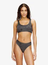 Top bralette color gris oscuro con estampado laminado de aspecto desgastado, escote redondo y banda elástica con logo de la marca.