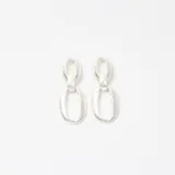 Aros colgantes de diseño minimalista, compuestos por dos eslabones ovalados de acabado mate y textura irregular en tono plateado.