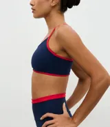 Top deportivo Get Over de corte nadador, confeccionado en microfibra azul marino con detalles en color rojo en los bordes y breteles. Presenta escote en U y copas integradas.