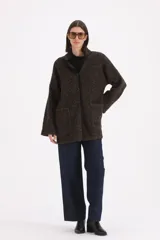 Saco 3/4 de tejido de punto texturizado en color marrón jaspeado, con cuello alto, cierre frontal de botones y bolsillos delanteros aplicados. Presenta detalles de ribetes en contraste a lo largo de la abertura frontal y el cuello.