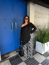 Conjunto de buzo asimétrico de manga larga con hombro descubierto y pantalón tiro alto de pierna ancha con estampado animal print tipo cebra, confeccionados en viscosa.