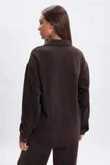 Sobrecamisa de pana en color marrón, con cuello clásico, cierre frontal con botones a presión y mangas largas con puños abotonados.