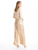 Pantalón de corte wide leg en tejido laminado metalizado color gris. Presenta pretina ancha elastizada con lazo de ajuste y bolsillos delanteros.