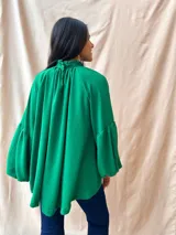 Blusa verde con cuello alto fruncido y mangas largas abullonadas.