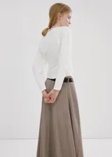 Blusa blanca de algodón con cuello asimétrico, detalles fruncidos, manga larga y cierre de cremallera lateral.