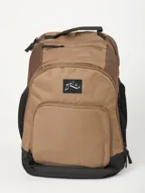 Mochila de color marrón claro y negro, con múltiples bolsillos frontales con cierre y logo de Rusty en negro. Presenta paneles laterales de malla negra y asa superior.