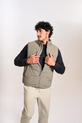 Chaleco puffer de corte regular, color beige, con cierre frontal y cuello alto. Presenta un diseño acolchado horizontal y logo bordado en el pecho.