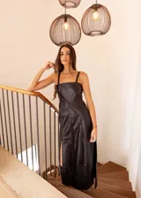 Vestido largo negro de cuero sintético, con breteles finos y corte recto con aberturas laterales.