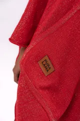 Ruana tejida de punto en algodón con destellos de lurex, de corte asimétrico y escote en V. Presenta una etiqueta de cuero con el logo de la marca en el frente.