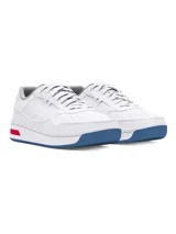 Championes Under Armour modelo Court 96, de diseño urbano en color blanco. Presentan una parte superior de cuero premium con perforaciones laterales para mayor ventilación, entresuela blanca con detalle de líneas horizontales rojas en el talón y suela de goma en tono azul translúcido.