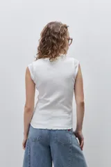 Remera sin mangas de silueta entallada y corte al cuerpo, confeccionada en algodón elastizado con textura acanalada y escote redondo.