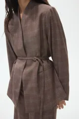 Blazer de corte recto con estampado a cuadros, escote en pico sin solapas y frente superpuesto. Presenta hombreras, bolsillos delanteros ribeteados, aberturas en los puños y un cinturón fino extraíble con anillas en D para ajustar en la cintura.