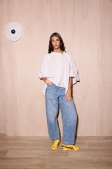 Camisa holgada de algodón con cuello alto y mangas anchas, confeccionada en Italia. Presenta un estampado de rayas verticales finas en tonos beige, blanco, amarillo, rojo y azul.