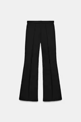 Pantalón de tiro alto confeccionado en crepe, con corte evasé y costuras frontales marcadas. Incluye un cinturón ajustable del mismo tejido con hebilla metálica y presenta cremalleras laterales ocultas en el bajo.