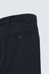 Pantalón chino de algodón color crema, corte regular fit, con cierre frontal de cremallera y botón, bolsillos delanteros y bolsillos traseros de vivo con botón.
