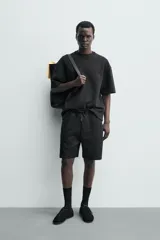 Bermuda estilo jogger de ajuste relajado, color negro, confeccionada en tejido interlock de algodón. Cuenta con cintura elástica ajustable mediante cordón, bolsillos delanteros tipo vivo y diseño liso.