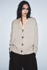 Chaqueta de punto color beige, confeccionada en 100% lana, con escote en pico, manga larga y cierre frontal con botones.