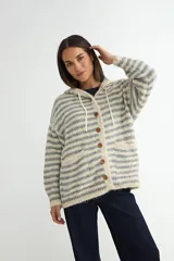 Saco tejido de punto con diseño a rayas horizontales en tonos beige y gris. Presenta capucha con cordones ajustables, cierre frontal con botones de madera, mangas largas y dos bolsillos delanteros.