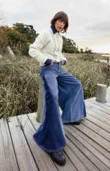 Pantalón de jean de tiro alto y pierna ancha, confeccionado en denim de algodón. Presenta un diseño de paneles en dos tonos de azul, con cortes triangulares en los laterales externos y ruedo deshilachado.