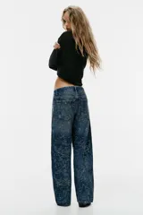 Jeans baggy de tiro medio con cinco bolsillos, trabillas para cinto y cierre frontal con cremallera y botón metálico. Cuenta con detalle de aplicación de brillos en toda la prenda.