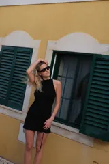 Vestido corto negro confeccionado en punto smock, con escote halter y detalle de volado en el ruedo.