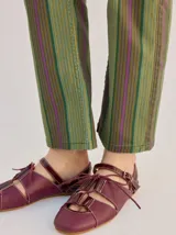 Sandalias planas tipo slingback de cuero marrón, con diseño delantero calado, cierre de cordones y tira trasera ajustable con hebilla.
