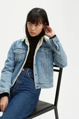 Campera de jean Levi's modelo Trucker, con interior y cuello forrados en corderito sintético color crema. Presenta cierre frontal con botones metálicos, bolsillos en el pecho con solapa y costuras reforzadas.