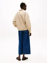 Campera bomber color beige, acolchada y repelente al agua, con cuello de béisbol, cierre frontal, puños y cuello de punto canalé, y dos bolsillos laterales ribeteados en diagonal.