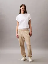 Pantalón jogger Calvin Klein de felpa color beige, con cintura elástica, bolsillos laterales y bajos de canalé. Cuenta con el monograma CK bordado en la pierna.