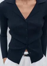 Cardigan de punto fino acanalado, color negro, con cuello en V con solapa y cierre frontal de botones.
