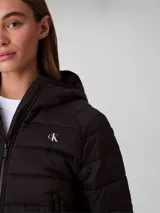 Campera puffer ligera Calvin Klein color negro, con diseño acolchado, capucha integrada, cierre frontal con cremallera y logo distintivo de la marca en el pecho.