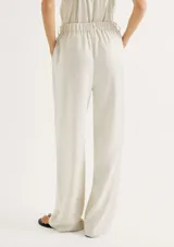 Pantalón de corte recto confeccionado en lino color beige, con cintura alta, bolsillos laterales y cinturón de cuerda ajustable con detalle de terminaciones metálicas.