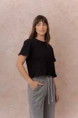 Remera negra de calce relajado y largo crop, con escote redondo, mangas cortas y ruedo terminados con delicados volados.