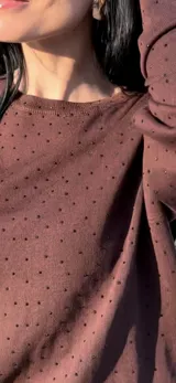 Conjunto de dos piezas compuesto por un sweater de manga larga y una falda larga de corte recto, confeccionado en tejido de punto color marrón.